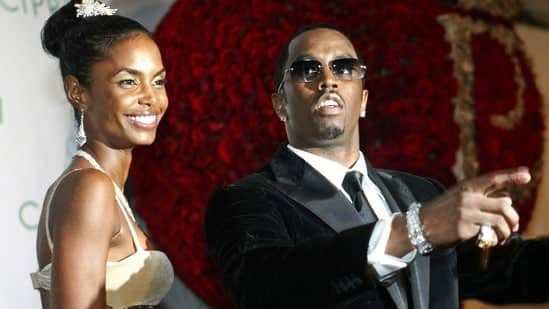 Sean "P. Diddy" Combs directs photographers as they sing "Happy Birthday," to him as his date Kim Porter, left, listens, after Combs arrived for his 35th birthday celebration at Cipriani on Wall Street in New York, Nov. 4, 2004. (AP)
