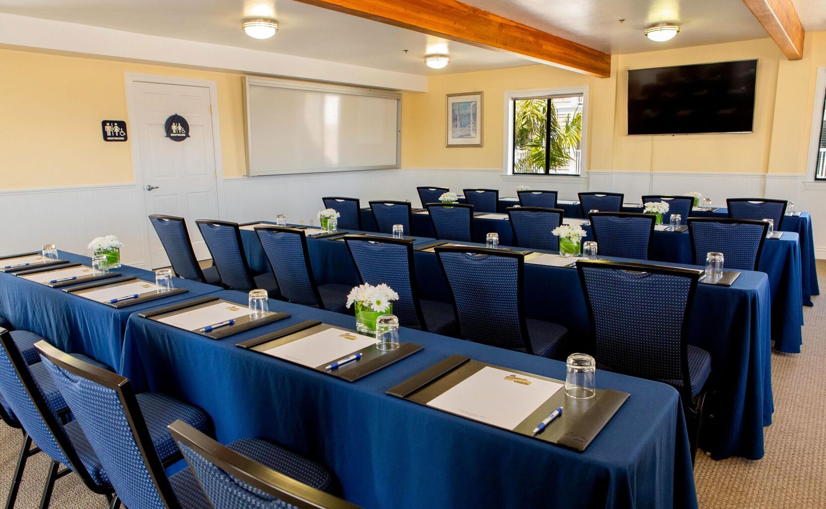 Pismo Lighthouse Suites Event Venues: Your Complete Guide to Beachfront Weddings, Meetings & Celebrations 2025 6 Conference and meeting room setup at Pismo Lighthouse Suites with blue tablecloths, notepads, and floral centerpieces, ideal for corporate and private events in Pismo Beach.