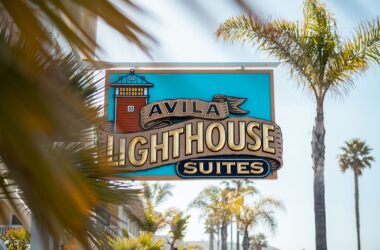 Best Oceanfront Hotel in Avila Beach: Luxury Suites & Central Coast Accommodations at Avila Lighthouse Suites 4 Avila Lighthouse Suites sign surrounded by palm trees in Avila Beach, California oceanfront hotel.