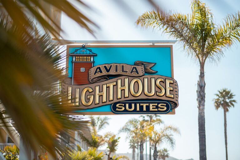 Best Oceanfront Hotel in Avila Beach: Luxury Suites & Central Coast Accommodations at Avila Lighthouse Suites 1 Avila Lighthouse Suites sign surrounded by palm trees in Avila Beach, California oceanfront hotel.