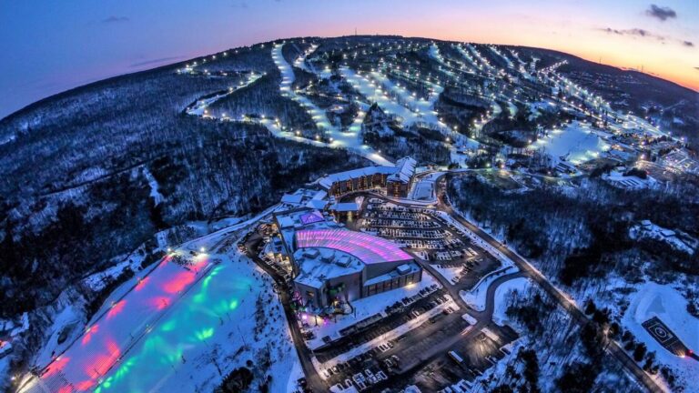 Experience the Thrill of Winter Sports at Blue Mountain Resort | Skiing & Snowboarding in Pennsylvania 2025 1 Aerial view of Blue Mountain Resort in the Pocono Mountains, Pennsylvania, glowing under twilight skies and showcasing ski trails, snow tubing areas, and illuminated slopes – Discover Pennsylvania's premier winter destination.