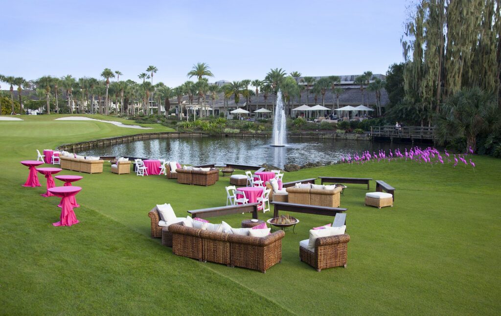 Best Hotels in Tampa Florida: Luxury Suites & Family-Friendly Stays at Saddlebrook Resort 21 Elegant outdoor event setup beside a tranquil pond at Saddlebrook Resort, featuring wicker seating, pink tables, and scenic views — showcasing why guests choose this Tampa resort repeatedly for its comprehensive resort experience beyond basic hotels.