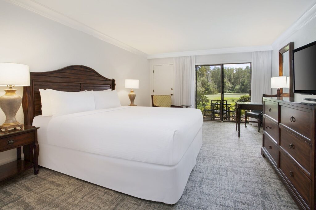 Best Hotels in Tampa Florida: Luxury Suites & Family-Friendly Stays at Saddlebrook Resort 13 Spacious suite with a king bed, elegant wooden furniture, and a private patio view — Accommodations Designed for Comfort and Style at Saddlebrook Resort.