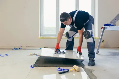 Epoxy Coating Calgary – Radiant Resin Inc 5 Professional installer laying large white floor tiles in a new construction or renovation project. Tile and Epoxy Coating Calgary services for durable floors.