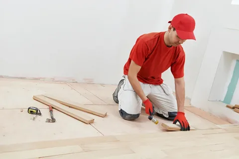 Transform Your Floors with Radiant Resin Inc: Epoxy Coating Calgary 9 Flooring contractor installing light-colored tongue-and-groove hardwood planks in a residential space in Calgary. Full installation services, including protective epoxy coating.